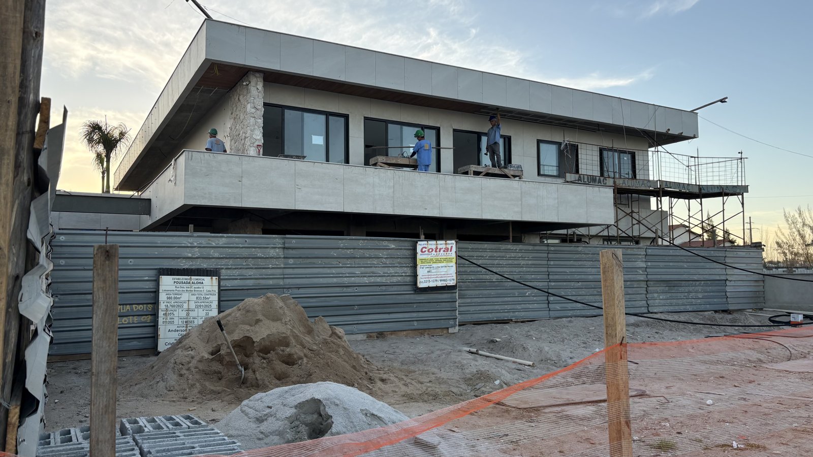 Casa em construção no Brasil em 2026, estrutura de concreto e alvenaria com operários trabalhando
